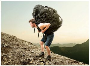 мужчина несет слишком тяжелый рюкзак для однодневных походов 
